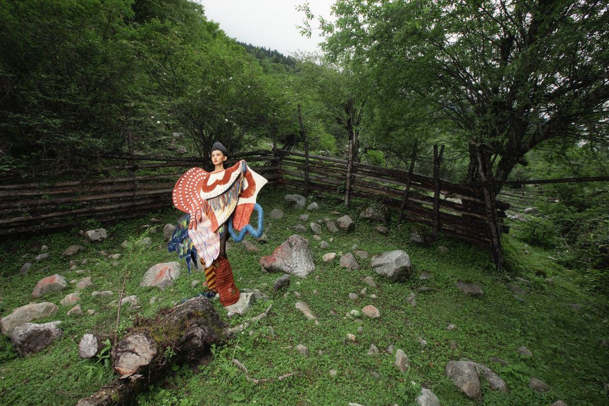 一位女士站在一个有岩石和围墙的田野中 手里拿着一把伞。