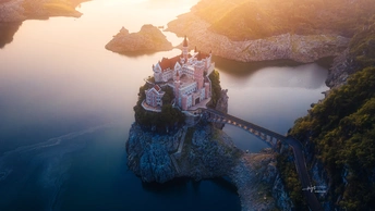 悬崖上的美丽城堡 俯瞰着被群山环绕的湖泊 上方有跨越水面的大桥。