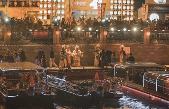 夜晚的城市 水中有许多人在船上 还有建筑物。