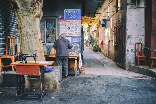 一个男子走在一条靠近一座老建筑的人行道上 街道上摆放着椅子和桌子。