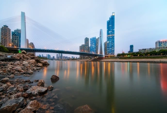 黄昏时分 一条河上有一座横跨其宽度的桥梁 天际线中有其他建筑和摩天大楼