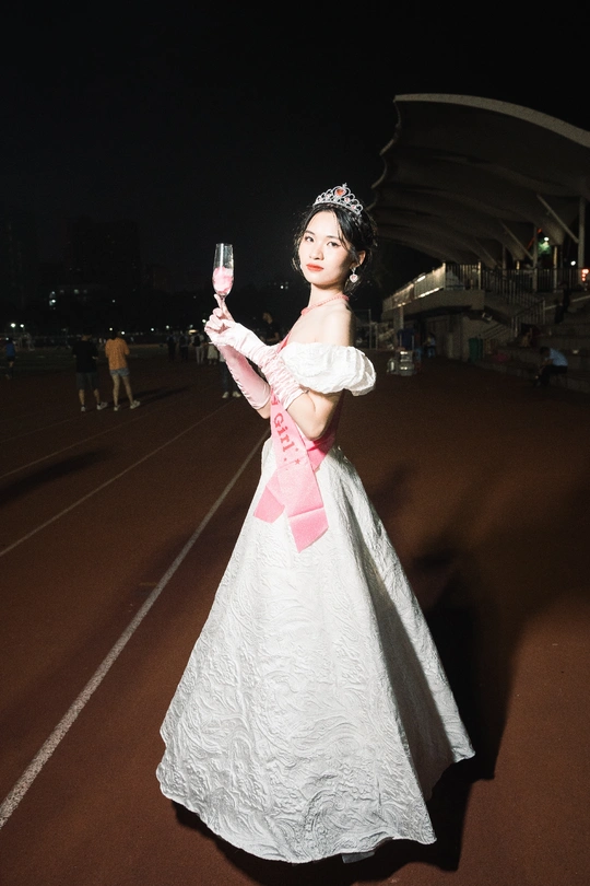 一位穿着白色连衣裙的年轻女子 右手拿着一杯酒。