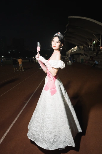 一位穿着白色连衣裙的年轻女子 右手拿着一杯酒。