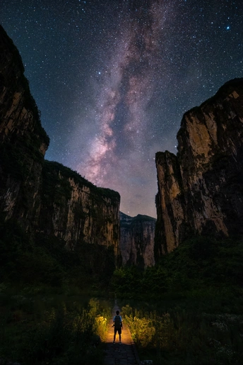 一个人站在山上看着夜空中的星星