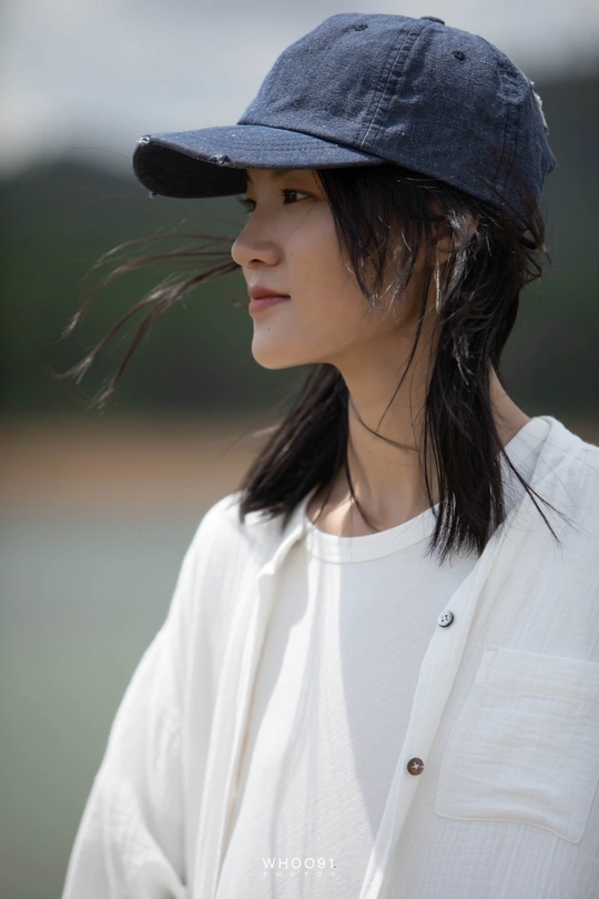 一位穿着白色衬衫和黑色帽子 头发飘在空中的年轻女子