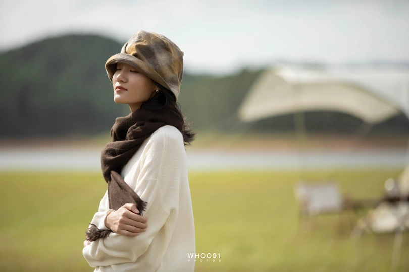 一位戴帽子和围巾的年轻女子站在田野中