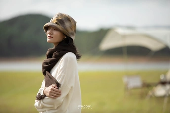 一位戴帽子和围巾的年轻女子站在田野中