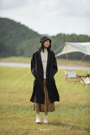 一位穿着长大衣和帽子站在田野里的女人