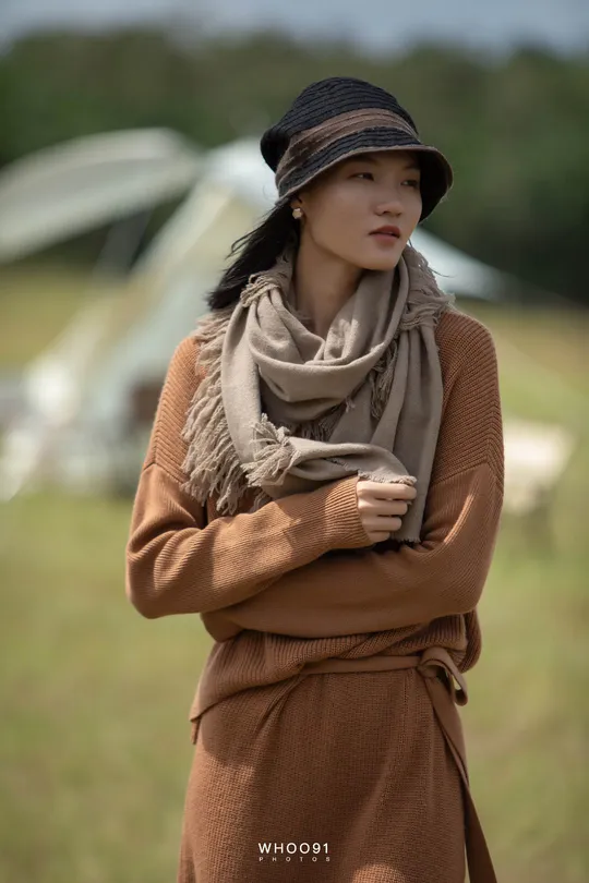 一位戴黑色帽子围巾的女士在田野中