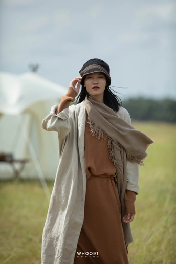 一位穿着外套和帽子站在白色帐篷前的年轻女子