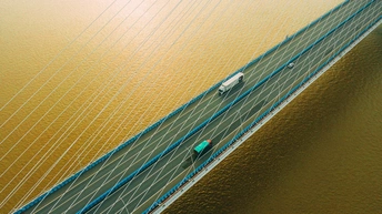 空中俯瞰一座长吊桥 桥上有汽车行驶 还有人在桥上。