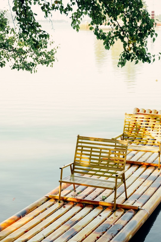 一个木制的长凳和椅子坐在湖面或水体上的小船顶部