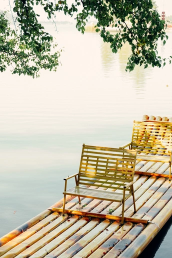 一个木制的长凳和椅子坐在湖面或水体上的小船顶部