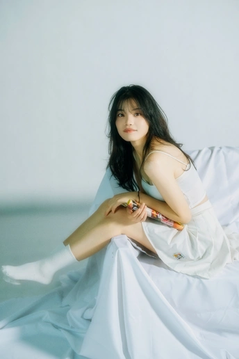 一位身穿白色连衣裙的年轻美女坐在白色背景照片上