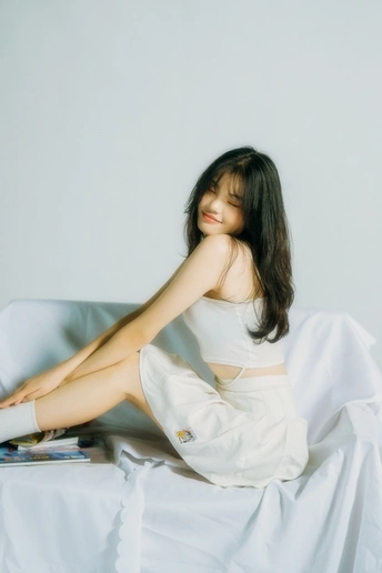 一个年轻的女人坐在铺着白色床单和书的床上