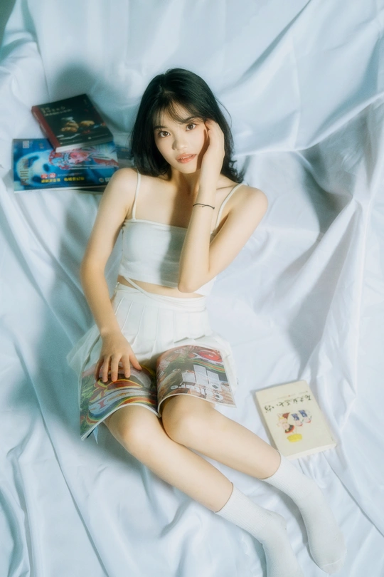 一个躺在床上的年轻女人 床上有白色床单和一本书