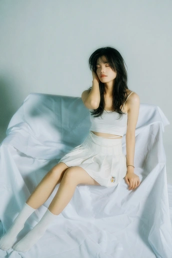一个穿着白裙子的年轻女人坐在床上