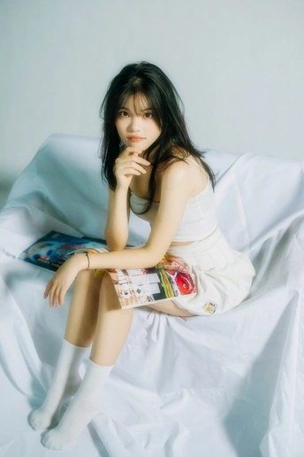 坐在铺着白色床单的床上的年轻女子