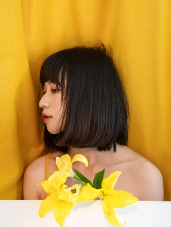 一个年轻的女人坐在桌子旁 头发上插着一朵黄色的花
