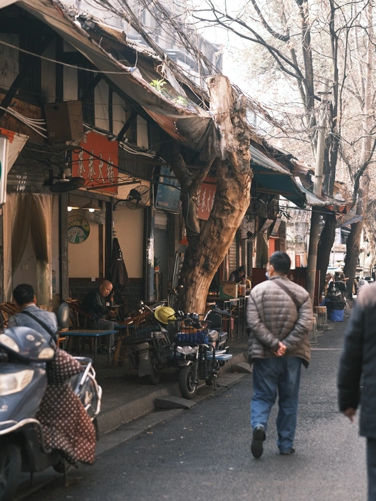 沿着停满摩托车的狭窄街道行走的人们