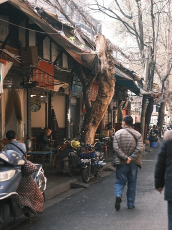 沿着停满摩托车的狭窄街道行走的人们