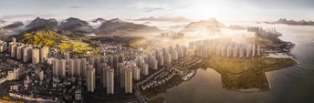 照片上有一个岛屿 有摩天大楼、水、山和太阳。