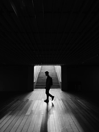 一个人拿着滑板走在黑暗的隧道里