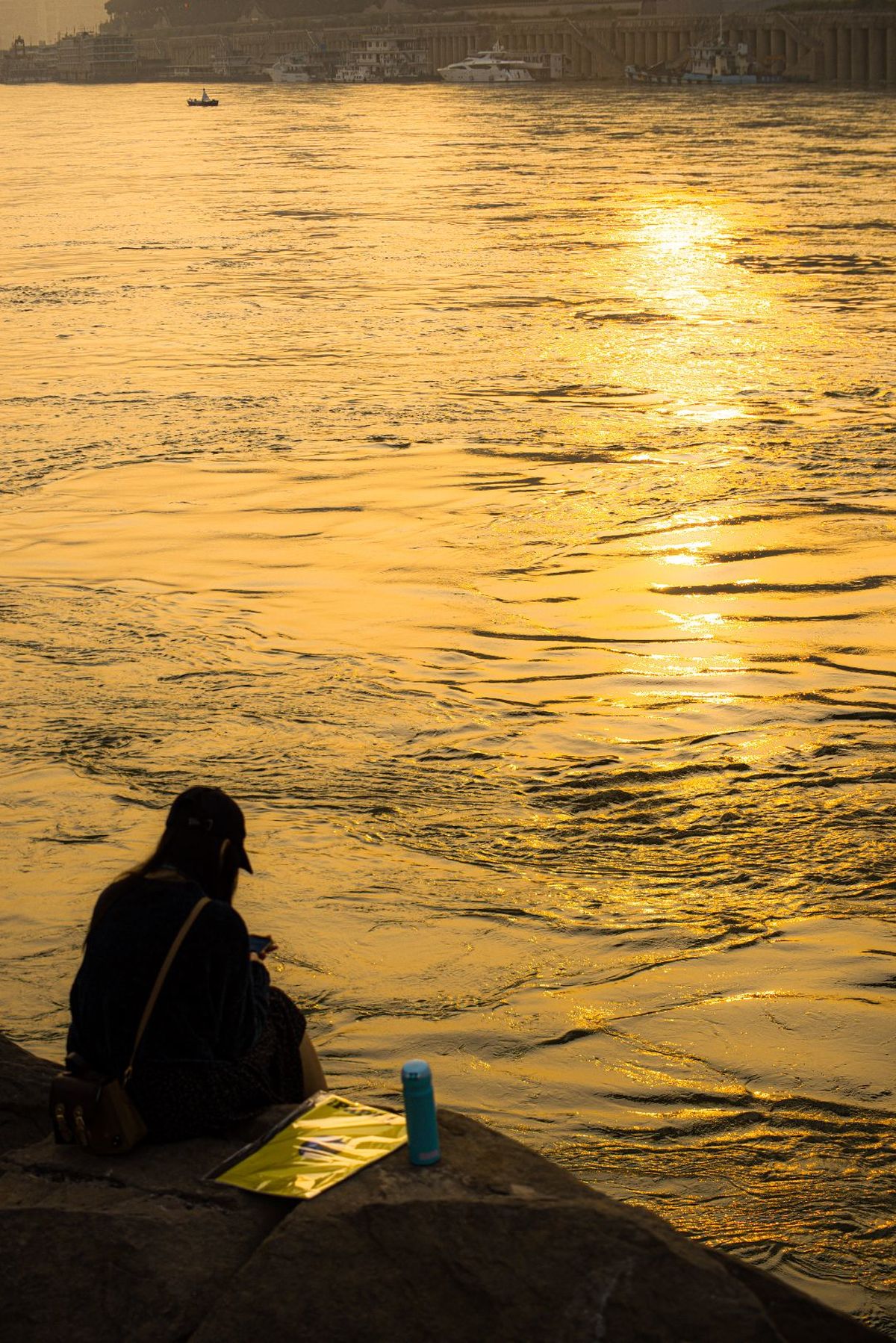 一位男性和一位女性坐在湖边 观看太阳在水面下沉落。