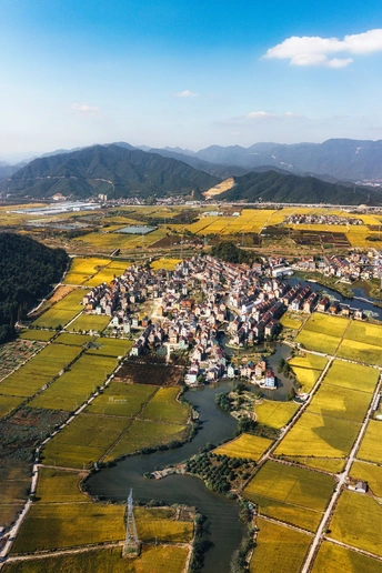 一个小村庄或小镇的 aerial view 周围有河流和远处的山脉。