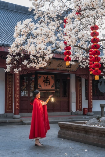一位穿着红裙子的年轻女子在寺庙的庭院中走动。