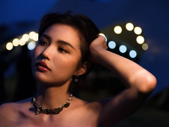 一位年轻女子戴着项链站在一组灯前