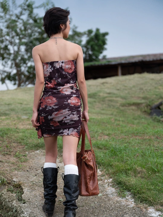 一位穿着花卉裙和靴子走路的女人