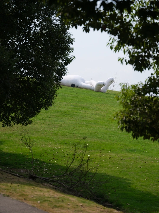 路边的绿色草地上有一座巨大的白色雕塑