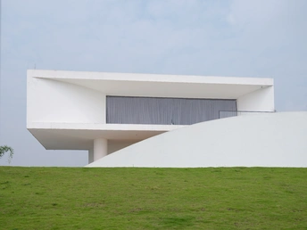 一座白色的现代房子坐落在山坡上 周围是绿色的草地。