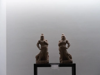 一尊女性雕塑站在另一个女性旁边