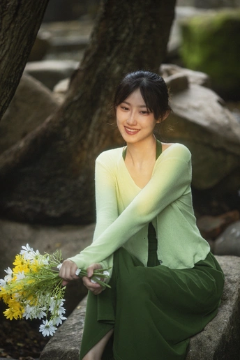 一个穿着绿色连衣裙的年轻女子手里拿着一束黄色的花