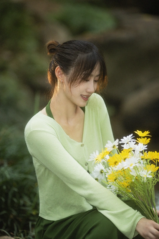 一个年轻的女人拿着一束黄色和白色的花坐在地上