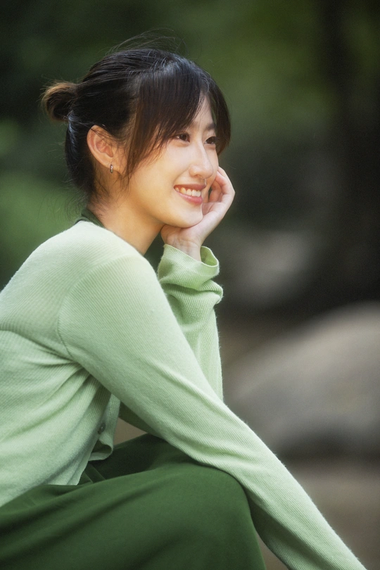 一位身穿绿色衣服的年轻女子坐着微笑