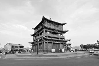 一张黑白照片 展示了一座位于城市中的古老中国建筑 前方有街道。
