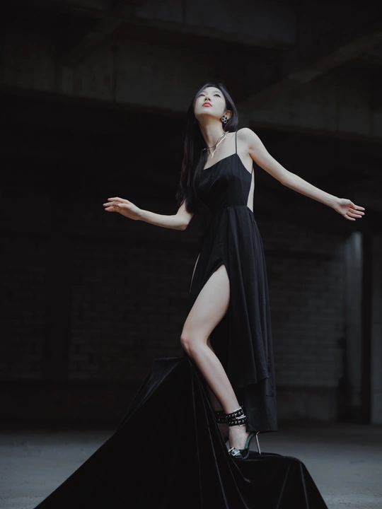 一个穿着黑色连衣裙的模特站在一个黑暗的地方。