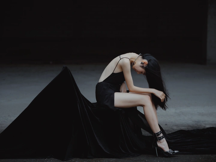 美丽的年轻女子穿着黑色连衣裙躺在地上