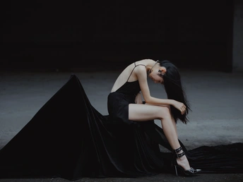 美丽的年轻女子穿着黑色连衣裙躺在地上