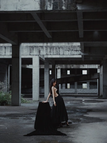 一个穿着黑色长裙的女人站在一座废弃的建筑中