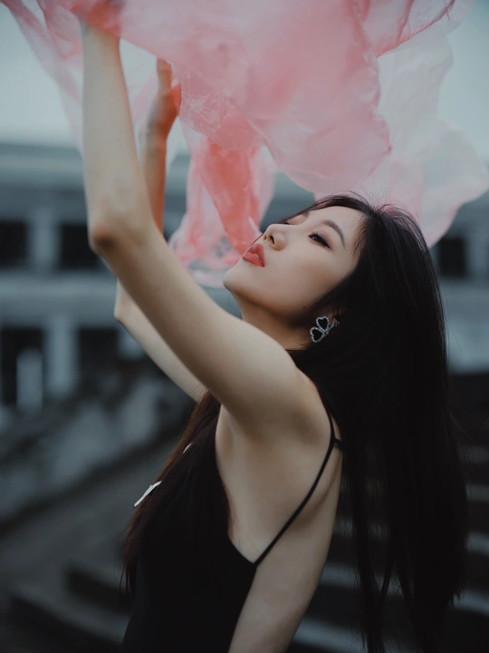 一位穿着黑色连衣裙的年轻女子拿着粉色雨伞