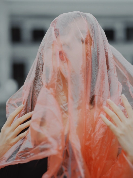 一位戴红雨衣遮住脸的女士 用塑料面罩遮住脸