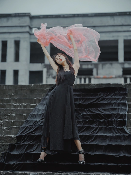 一位穿着黑色连衣裙 拿着粉色雨伞的女人