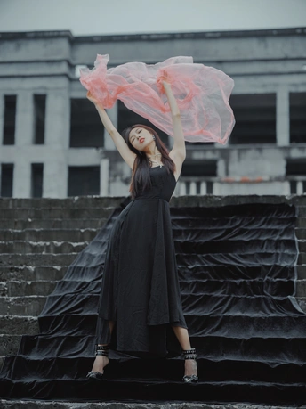 一位穿着黑色连衣裙 拿着粉色雨伞的女人