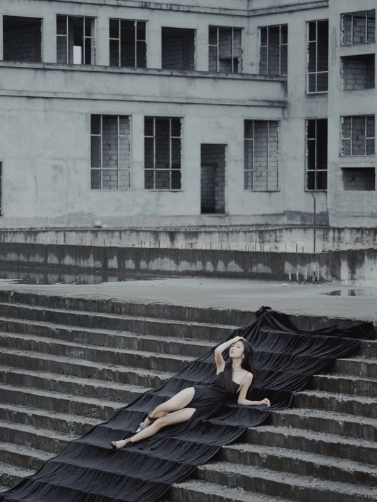 一个穿着黑色连衣裙的女人躺在建筑物的台阶上