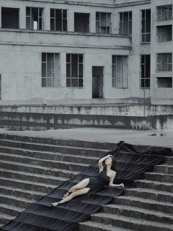一个穿着黑色连衣裙的女人躺在建筑物的台阶上