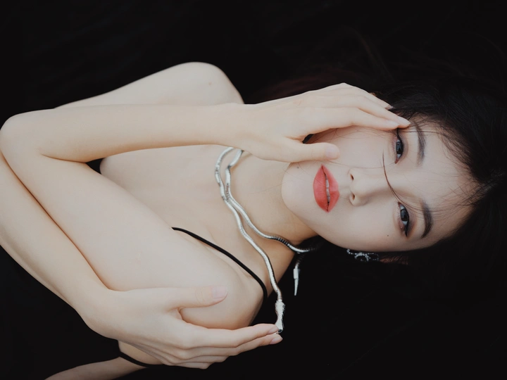 一个年轻女子躺在黑色背景上 手举在空中 正在听音乐。